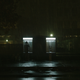 A man uses a payphone on a dark, wet street.